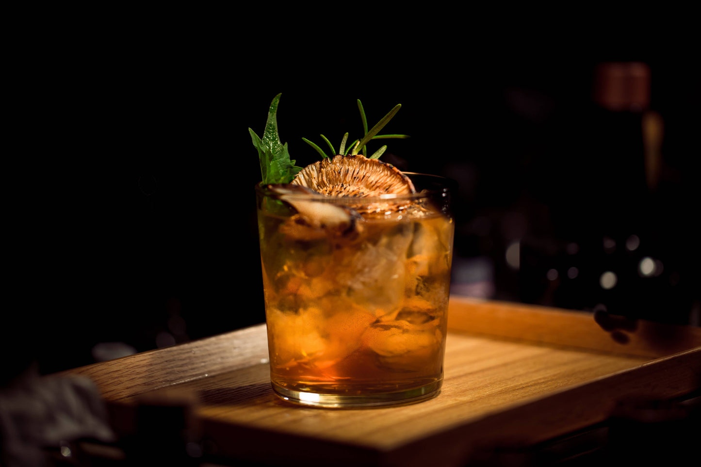 Cocktail with ice and garnish on a wooden surface with a dark background