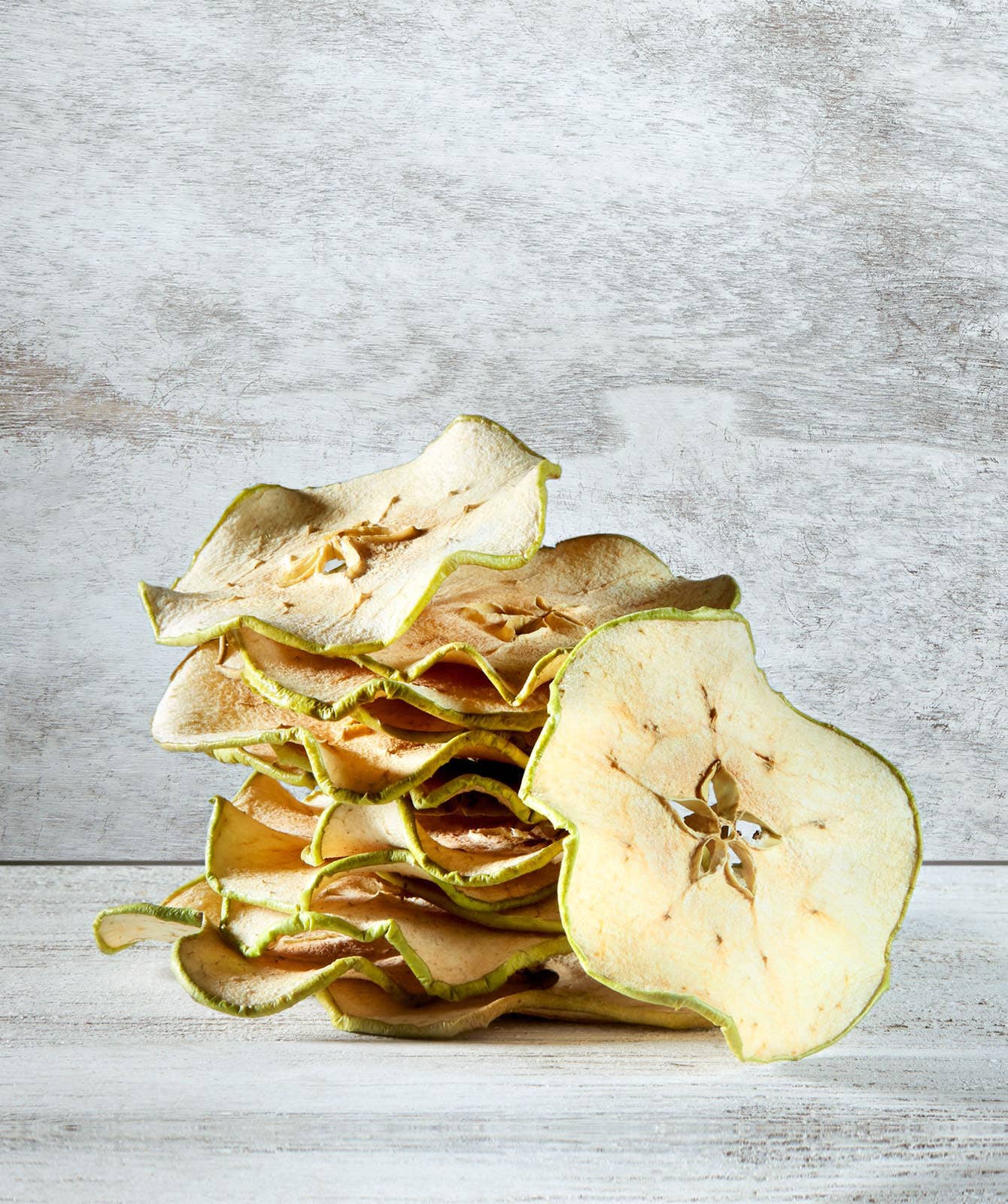 Stack of dried pear slices on a textured wooden surface