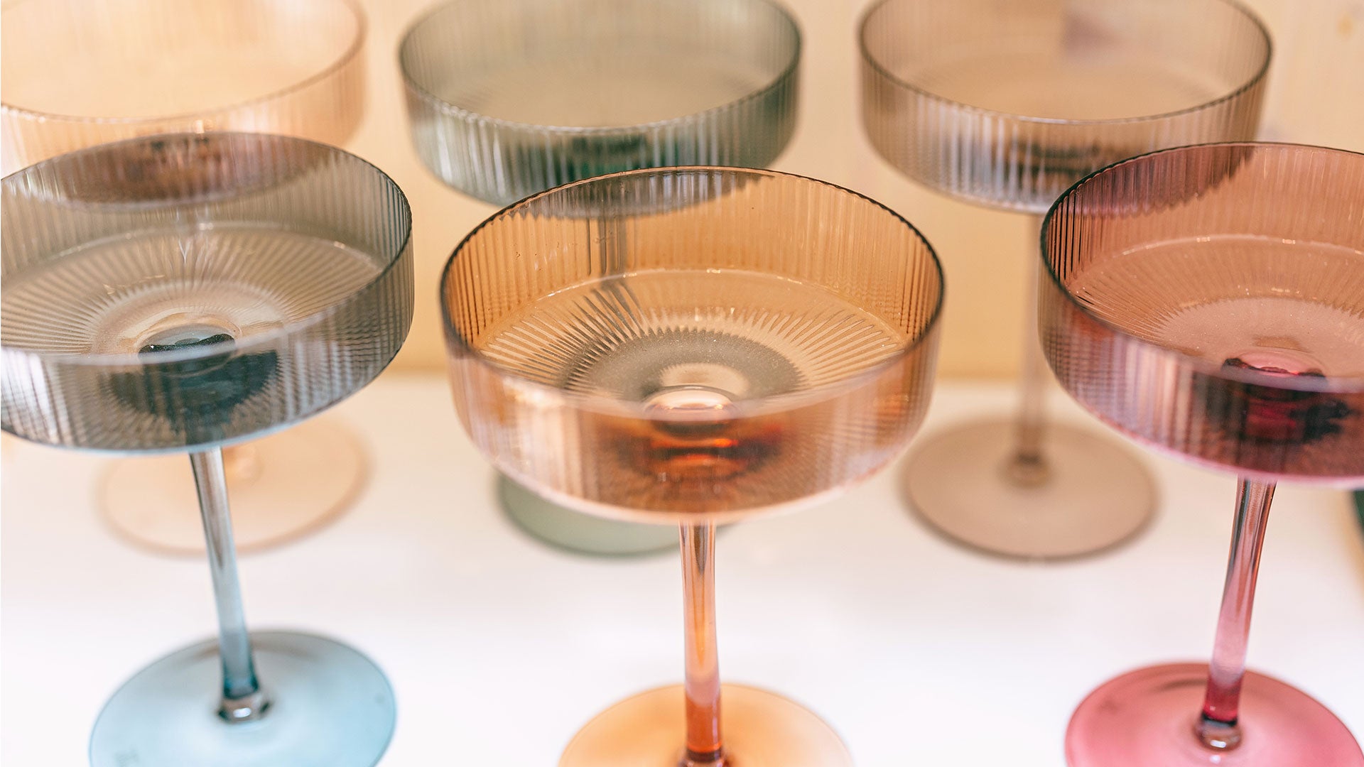 Beautiful multi-colored vintage coupe glasses on a shelf.