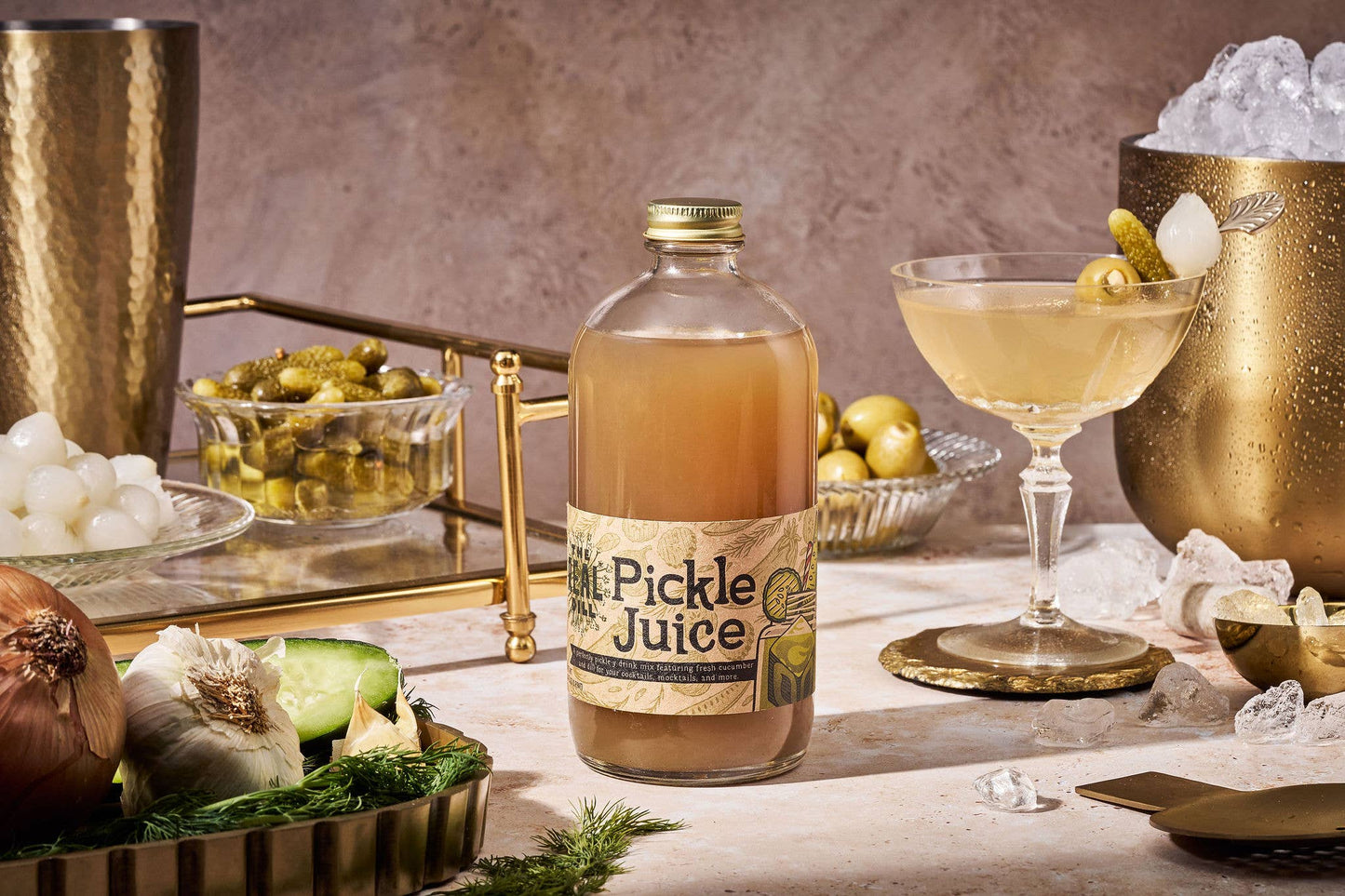Bottle of 'Pickle Juice' with a cocktail and ingredients on a bar setup.