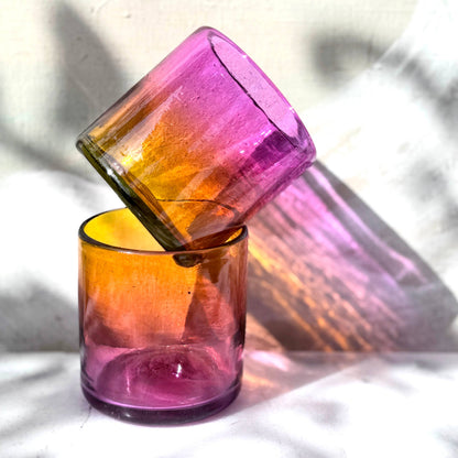Two multicolored glass tumblers stacked on a light background