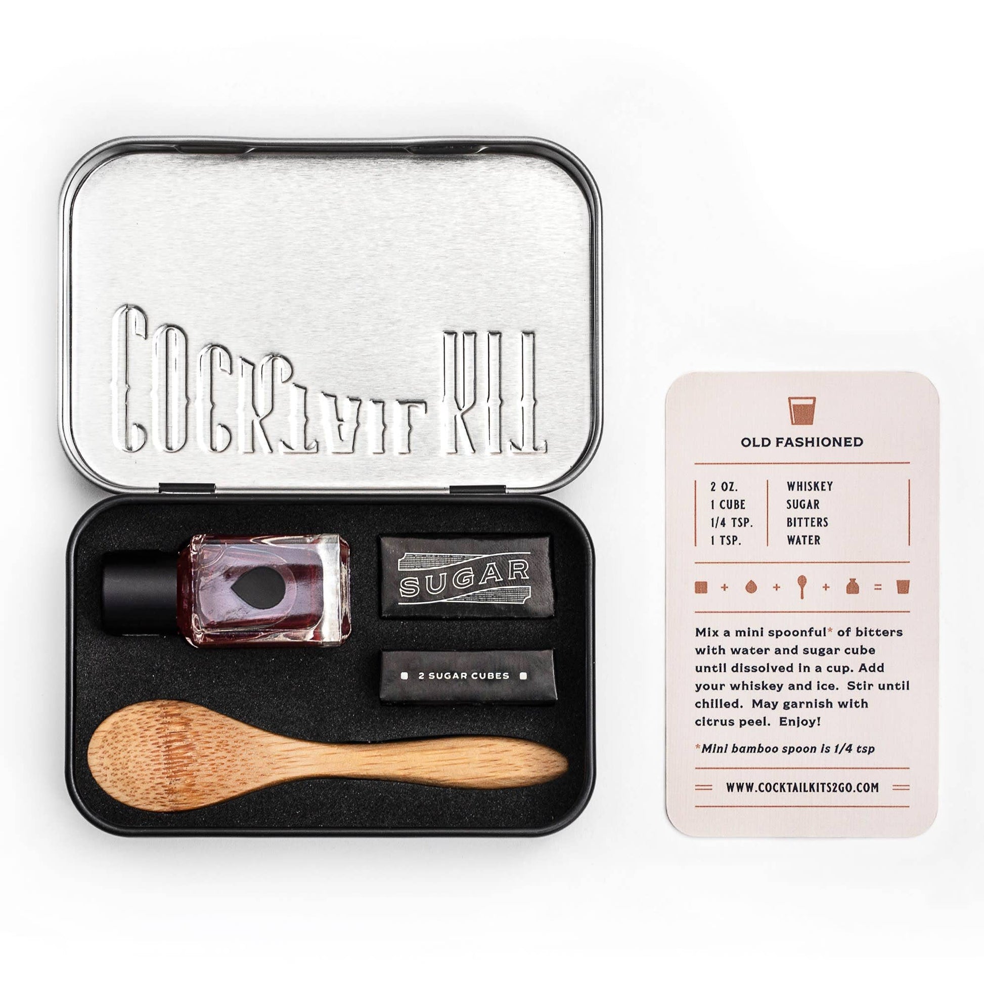 Cocktail kit with ingredients and tools in a black tin on a white background