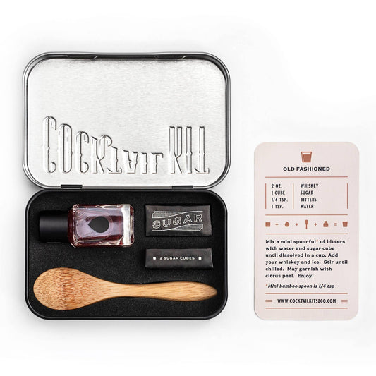 Cocktail kit with ingredients and tools in a black tin on a white background