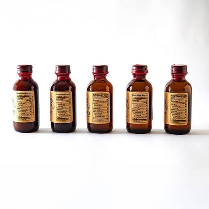 Five brown bottles with labels on a white background