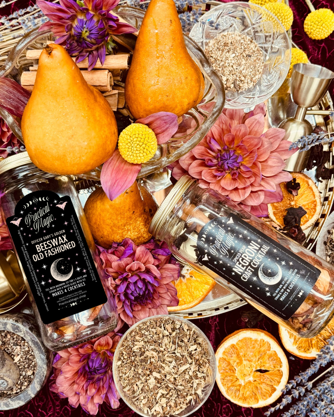 Two bottles of 'Black Magic' Beeswax Old Fashioned with decorative elements like oranges, flowers, and herbs.