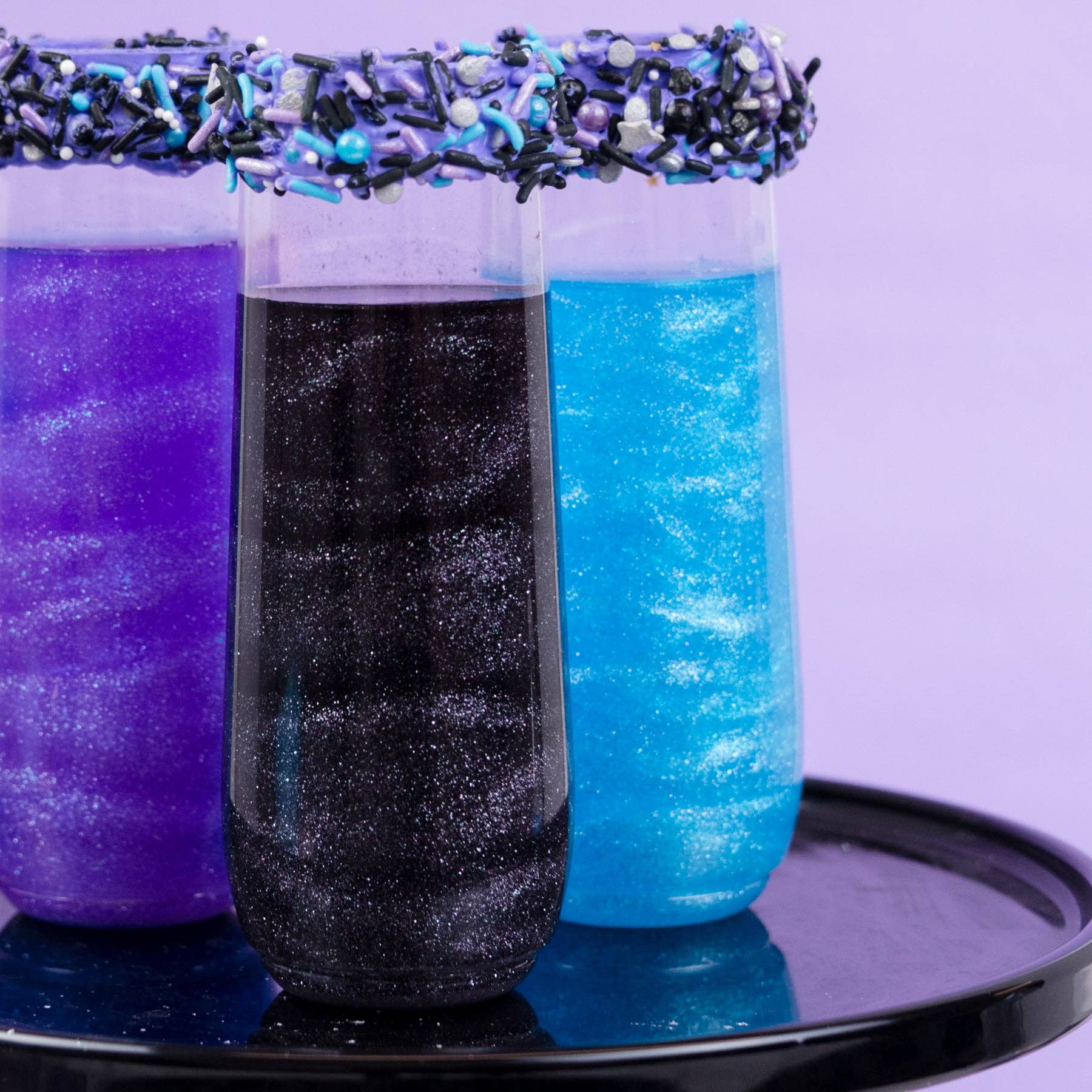Three layered drink with purple, black, and blue colors on a white background