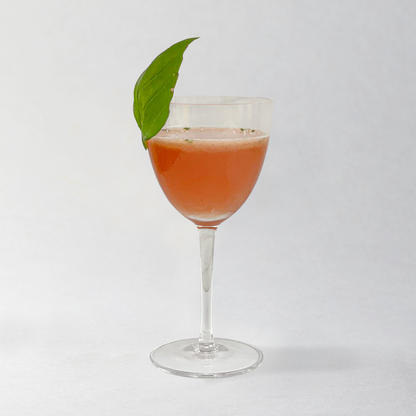 Cocktail in a glass with a green leaf garnish on a white background
