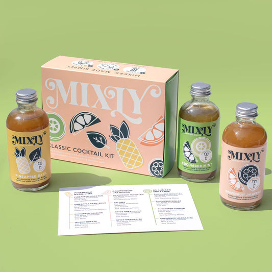 A gift set of Mixly Classic Cocktail Kit, featuring three bottles of cocktail mixers in different flavors (Pineapple Basil Lime, Grapefruit Jalapeno, and Cucumber Mint Lime) with a recipe card on a green background.