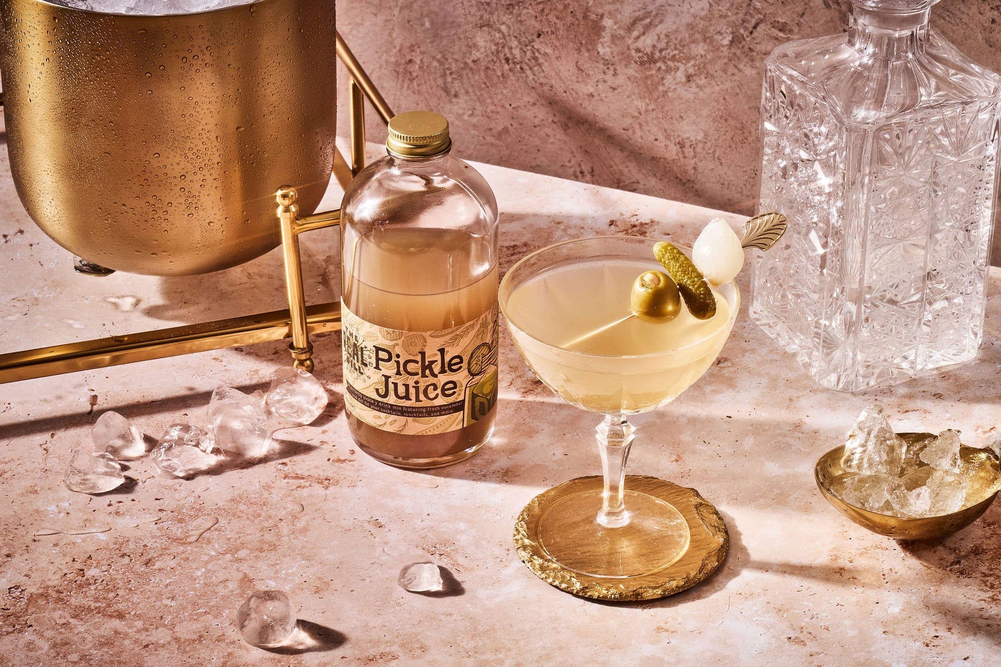 Bottle of 'Pickle Juice' with a cocktail garnished with a pickle on a bar counter.