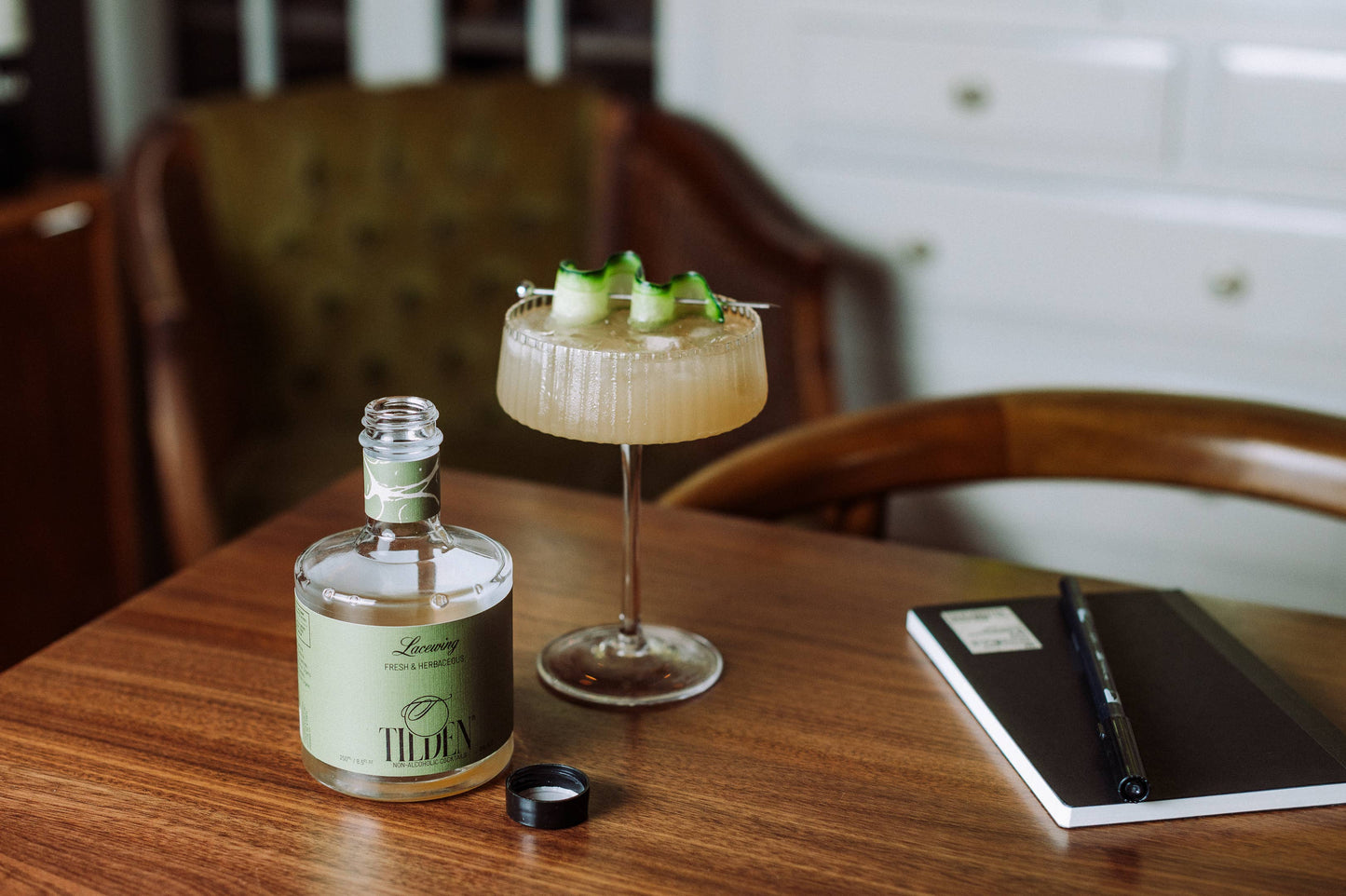 Bottle of Tiden Lacewing Non-Alcoholic with a cocktail on a wooden table