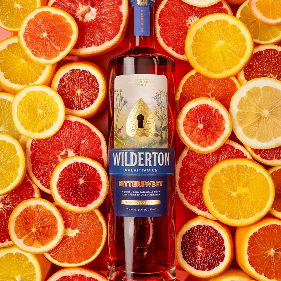 Bottle of Wilderton aperitivo surrounded by sliced citrus fruits on a colorful background